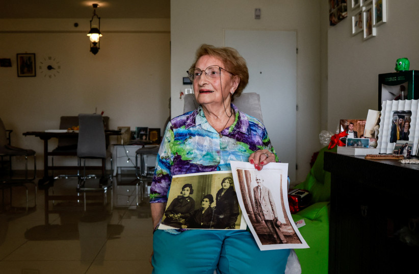  Holocaust survivor, Sarina Blumenfeld, 89, who endures flashbacks from the horrors of her past and now struggles to process the carnage following a deadly infiltration by Hamas gunmen, shows black and white photos during an interview with Reuters in her home in Ashdod, southern Israel, October 23 (credit: REUTERS/AMMAR AWAD)