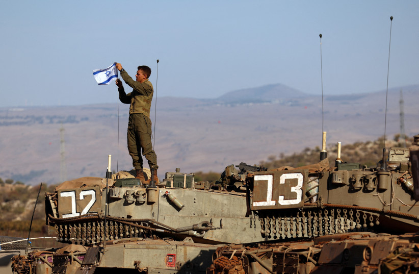  A soldier installs an Israeli flag on a tank during a military drill near Israel's border with Lebanon in northern Israel, October 26, 2023 (credit: REUTERS/LISI NIESNER)