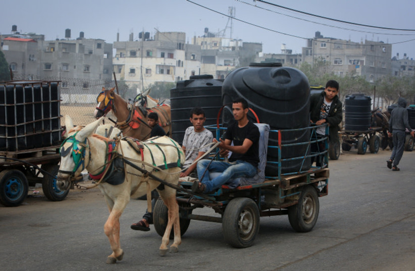  Palestinian civilians wait to collect water using horse and donkey drawn carts, in Rafah in the southern Gaza Strip, on October 28, 2023 (credit: ABED RAHIM KHATIB/FLASH90)