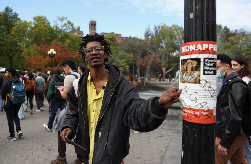  A man rips off a poster with a picture of a woman and the word ''kidnapped'', as part of a student walkout by students of New York University, in New York City, U.S., October 25, 2023.  (credit: REUTERS/SHANNON STAPLETON)