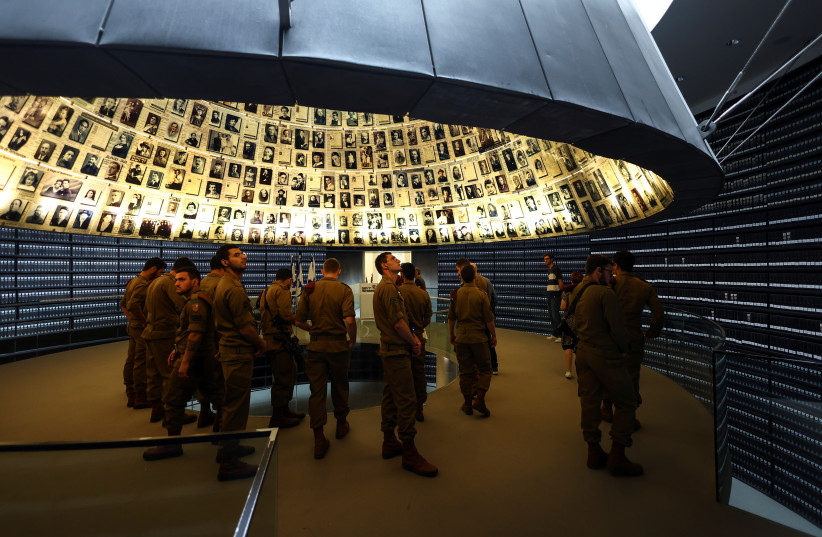  Israeli soldiers look up at pictures of victims of the Holocaust at the Yad Vashem Holocaust memorial centre, ahead of the Holocaust Remembrance Day starting this evening, at the Hall of Names, in Jerusalem April 27, 2022. (credit: REUTERS/Ronen Zvulun)