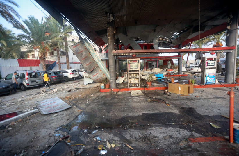  Palestinians walk past rubble of a gas station destroyed in an Israeli airstrike in the Gaza Strip, on October 24 2023. (credit: ATIA MOHAMMED/FLASH90)