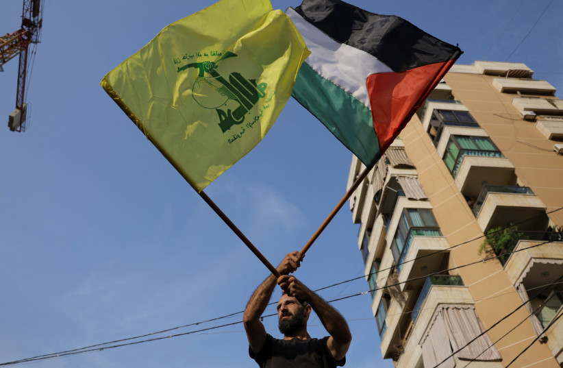 Um homem segura bandeiras do Hezbollah e da Palestina enquanto apoiadores do Hezbollah protestam em solidariedade aos palestinos em Gaza, em meio ao conflito em curso entre Israel e o grupo islâmico palestino Hamas, em Beirute, Líbano, 27 de outubro de 2023. (crédito: REUTERS/AMR ALFIKY)