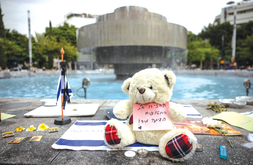 FLAGS, CANDLES, flowers, and a teddy bear with a sign that reads ‘Return the hostages home immediately!’ are placed at Dizengoff Square in Tel Aviv. ( Chaim Goldberg/Flash90)