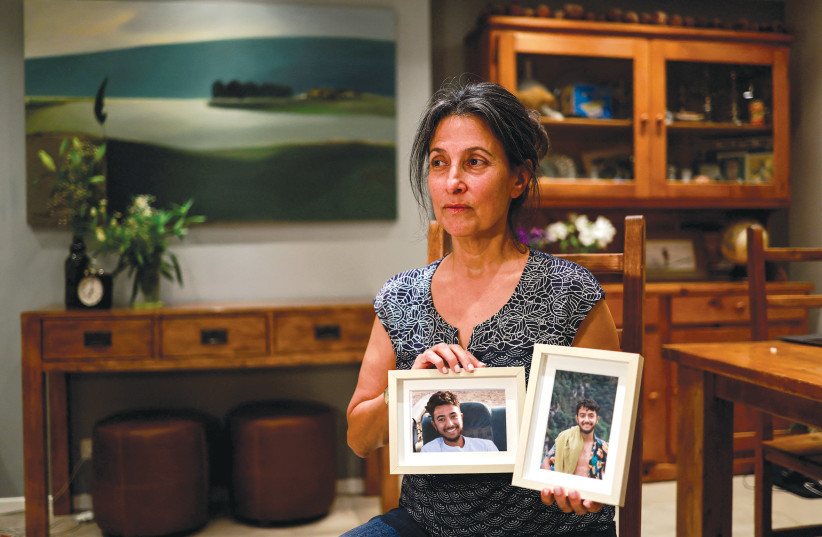 Rachel Goldberg, the mother of Hersh Goldberg Polin, who was taken hostage by Hamas terrorists while attending a music festival in southern Israel, holds photographs of her son in their home in Jerusalem on October 17 (credit: AMMAR AWAD/REUTERS)