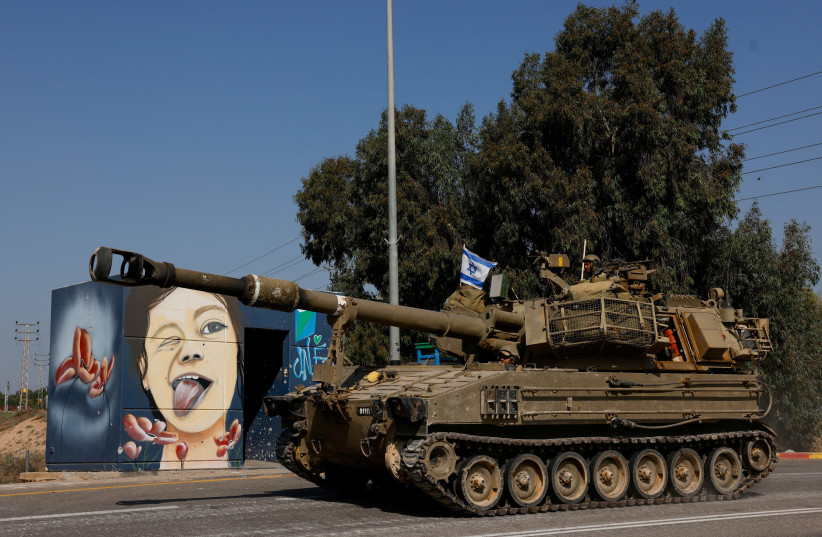  View of a mural as Israeli soldiers from an artillery unit ride a military vehicle near the Israeli side of the border between Israel and the Gaza Strip, November 3, 2023 (credit: REUTERS/AMIR COHEN)