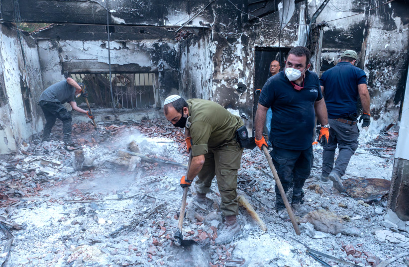  Israel Antiquities Authority workers sift through the ash of a burned-out house in Kibbutz Be'eri. (credit: Israel Antiquities Authority)