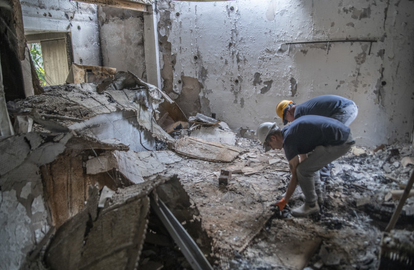 Israel Antiquities Authority workers in one of the houses in Kibbutz Be'eri destroyed by Hamas. (credit: Israel Antiquities Authority)