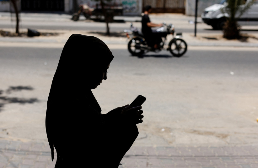  A Palestinian woman uses a Phone app that allows Gaza women to report domestic abuse anonymously, outside Gaza Women's Center in Gaza City May 31, 2022 (credit: REUTERS/MOHAMMED SALEM)