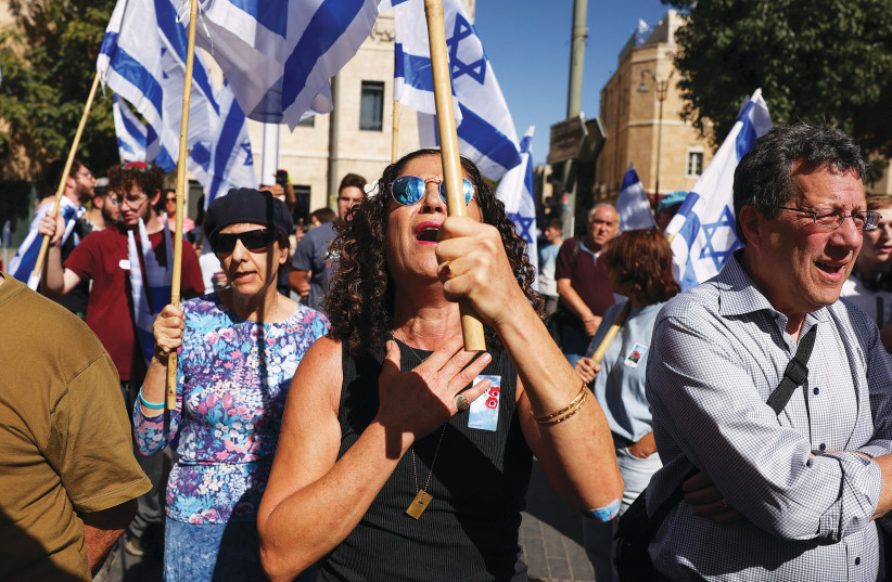  PEOPLE HOLD Israeli flags during a ceremony in early November in Jerusalem to mark the one-month anniversary of the October 7 Hamas massacre. (credit: RONEN ZVULUN/REUTERS)
