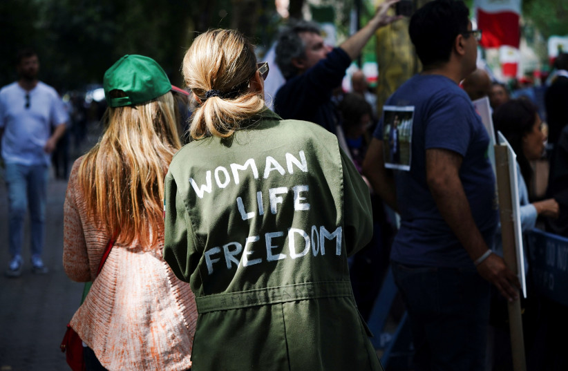 A woman wearing a jacket painted with the slogan ''Woman Life Freedom'' walks past a demonstration by supporters of the Mujahideen-e-Khalq (MEK), an Iranian dissident group, near the United Nations headquarters during the visit of Iran's President Ebrahim Raisi in New York, September 19, 2023.