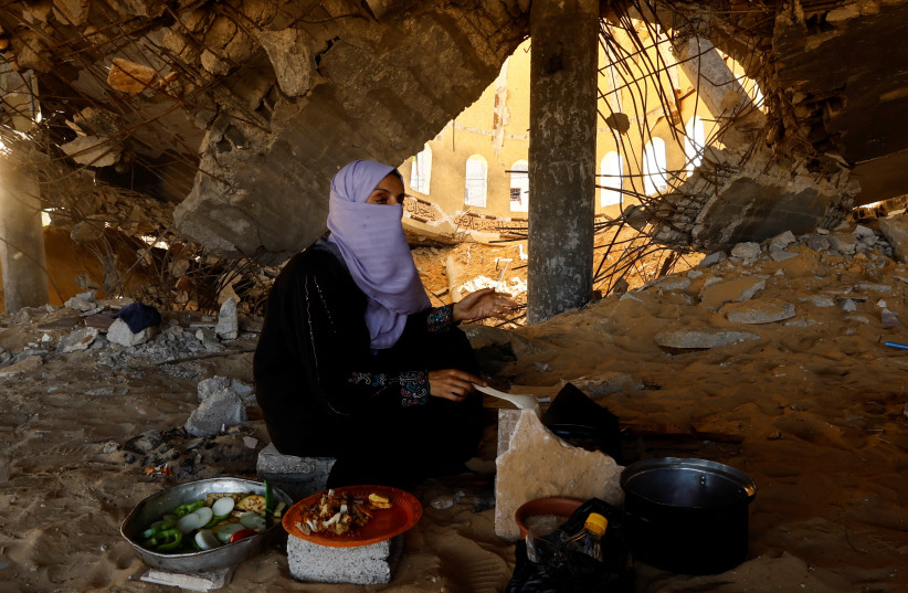 A woman cooks, amid shortages of food supplies and fuel, as the conflict between Israel and Palestinian terrorist group Hamas continues, in Khan Younis in the southern Gaza Strip November 17, 2023. (credit: IBRAHEEM ABU MUSTAFA/REUTERS)