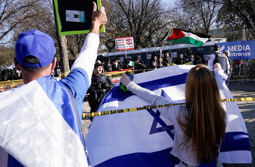  A rally goer holds up an Israeli flag towards counter protesters, as Jewish Americans and supporters of Israel gather in solidarity with Israel and protest against antisemitism, amid the ongoing conflict between Israel and Hamas, in Washington, U.S, November 14, 2023. (credit: REUTERS/Elizabeth Franz)