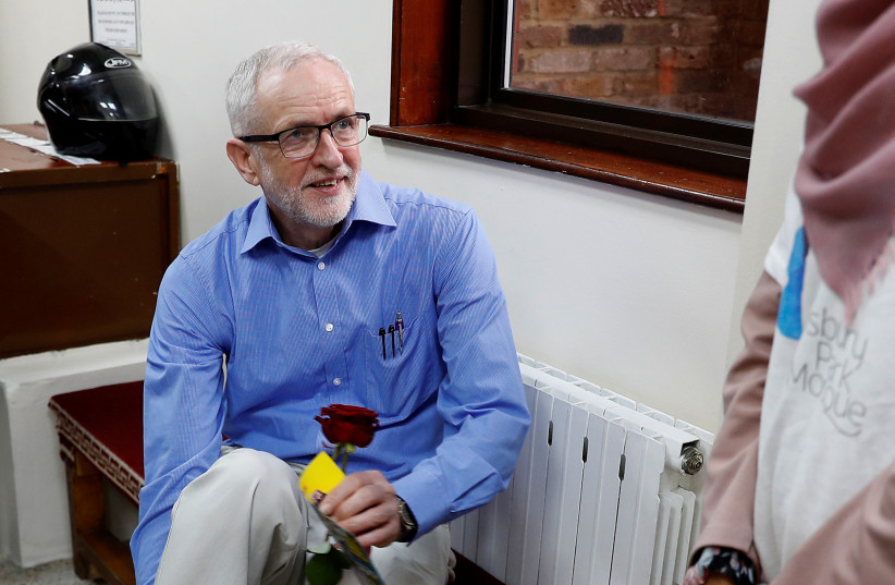 Britain's opposition Labour Party leader, Jeremy Corbyn, removes his shoes during a visit to Finsbury Park Mosque, on Visit My Mosque day, in London, Britain, March 3, 2019. (credit: PETER NICHOLLS/REUTERS)