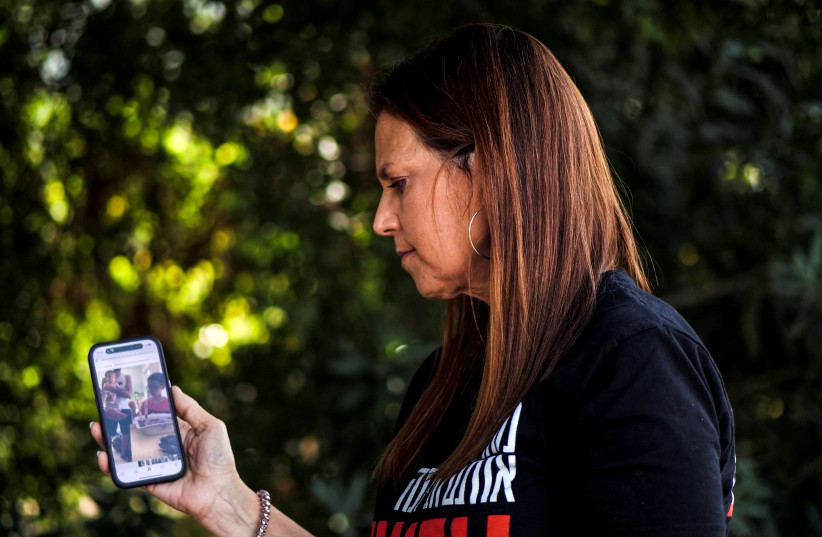 Merav Raviv, a relative of Ohad Munder who was taken hostage with his mother and grandparents, during a deadly infiltration by Hamas terrorists from Gaza, watches a video of a family celebration on her phone in Neve Ilan, Israel October 23, 2023.