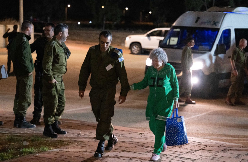  Adina Moshe takes the arm of an IDF representative as she returns to Israel. (credit: IDF SPOKESMAN’S UNIT)