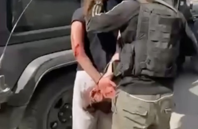  A screenshot from a video of Hamas taking hostages into Gaza on October 7. In this video, the terrorist drags the Israeli hostage by her hair from the trunk of the vehicle to the backseat while crowds gather and cheer. The crotch of the hostage’s pants is bloodstained, and her right Achilles tendon (credit: screenshot)
