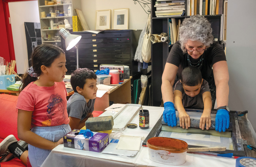  YAEL BOVERMAN-ATTAS helps a youngster from the South come to grips with silkscreen printing.  (credit: YAEL ILAN)
