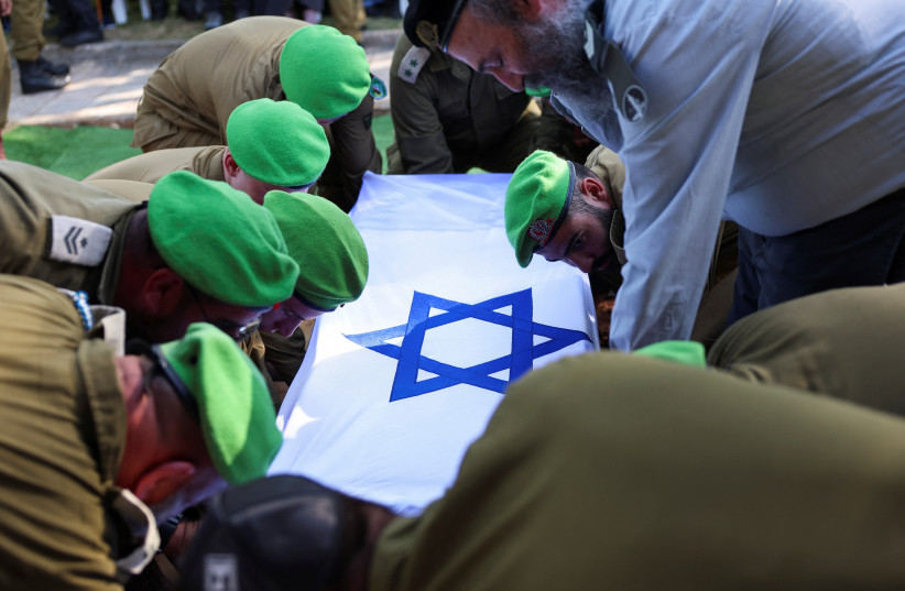 A national flag is draped over a coffin as friends and family mourn Israeli soldier Staff Sergeant Aschalwu Sama who died of wounds obtained in November during the ground invasion by Israel's military in the northern Gaza Strip, at his funeral in Petah Tikva, Israel December 3, 2023.  (credit: REUTERS/ATHIT PERAWONGMETHA)