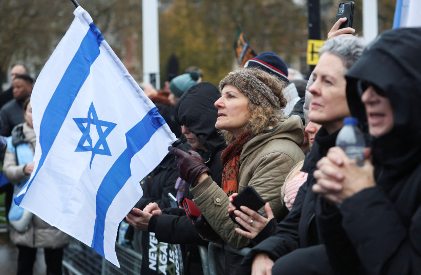  A demonstrator holds an Israeli flag as they attend a march against antisemitism, during a temporary truce between the Palestinian Islamist group Hamas and Israel, in London, Britain November 26, 2023. (credit: REUTERS/Susannah Ireland)