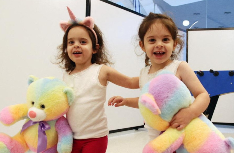  Twins Yuli Cunio, 3, and Emma Cunio, 3, who were taken hostage during the October 7 attack by Hamas, hold toy bears shortly after their arrival in Israel, at Schneider Children's Medical Center of Israel in Petah Tikva, Israel, November 27, 2023 (credit: SCHNEIDER CHILDREN'S MEDICAL CENTER/HANDOUT VIA REUTERS )