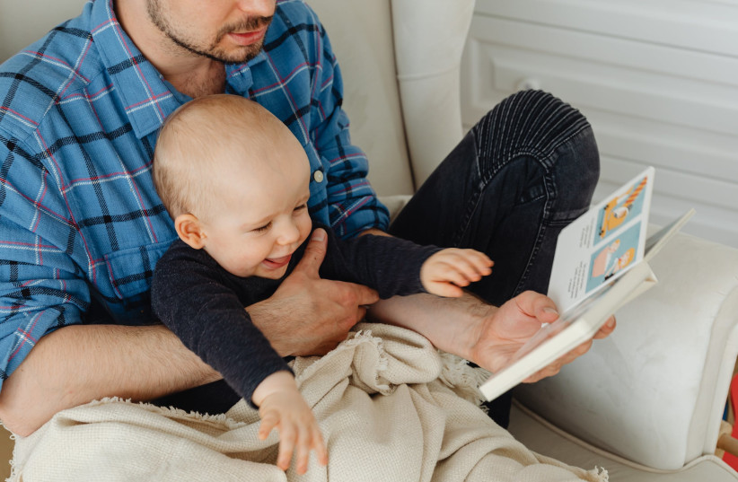 Father reading to a baby boy. (credit: PEXELS)