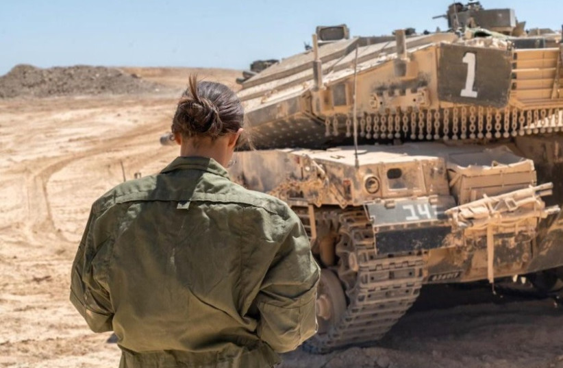  A female IDF soldier stands in front of a tank. (credit: IDF)