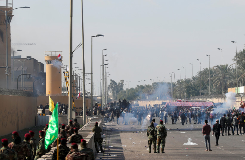 U.S. Embassy security men use stun grenades to disperse protesters and militia fighters during a protest to condemn air strikes on bases belonging to Hashd al-Shaabi (paramilitary forces), outside the embassy in Baghdad, Iraq January 1, 2020. (credit: THAIER AL-SUDANI/REUTERS)