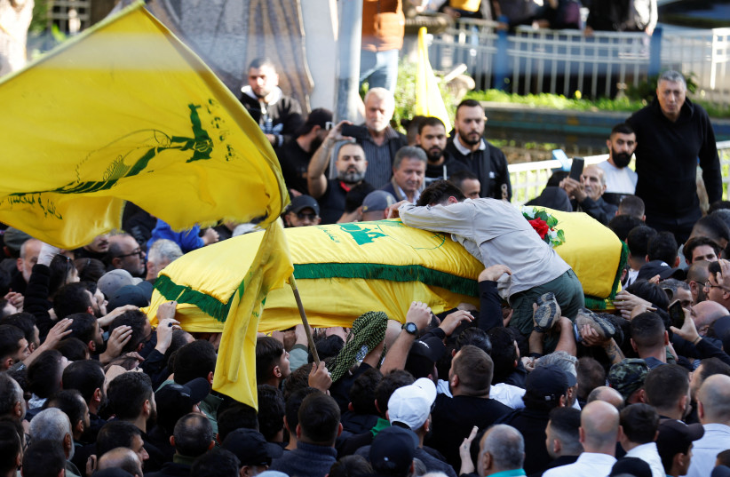 A man climbs on the coffin of Hezbollah member Abbas Raad, senior Hezbollah figure and member of parliament Mohammad Raad's son. (credit: ALAA AL-MARJANI/REUTERS)