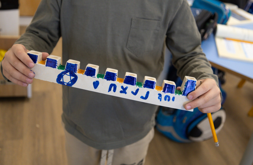  A child holds a hanukkiah they decorated for IDF soldiers operating in Gaza. December 2023 (credit: IDF SPOKESPERSON'S UNIT)