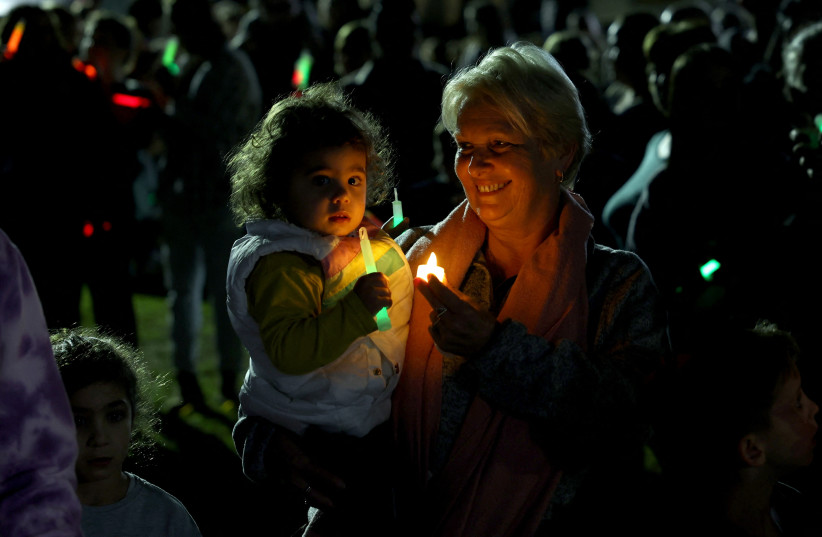  Displaced community members from Kibbutz Kfar Aza, which was hit hard following the deadly October 7 attack by gunmen from Palestinian militant group Hamas from the Gaza Strip, light Hanukkah candles and call for release of all hostages during a ceremony at Kibbutz Shefayim, Israel December 10, 202 (credit: RONEN ZVULUN/REUTERS)