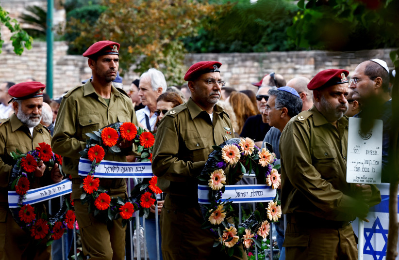  Israeli soldiers carry flowers at the funeral for Israeli reserve soldier Master Sergeant Omri Ben Shachar, who was killed during the ongoing ground operation by Israel's military against Hamas in Gaza, at Kiryat Shaul cemetery in Tel Aviv, Israel, December 10,  (credit: REUTERS/CLODAGH KILCOYNE)