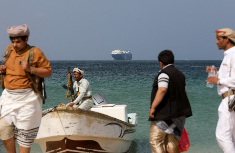 Armed men stand on the beach as the Galaxy Leader commercial ship, seized by Yemen's Houthis last month, is anchored off the coast of al-Salif, Yemen, December 5, 2023 (credit: REUTERS/KHALED ABDULLAH)