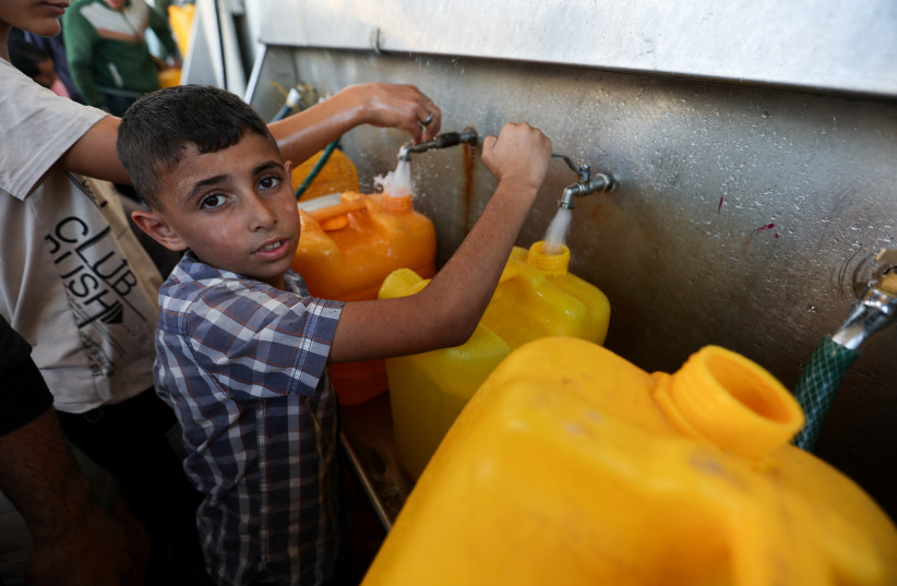  A Palestinian boy fills a container with water, amid the ongoing conflict between Israel and the Palestinian terrorist group Hamas, in Khan Younis, in the southern Gaza Strip, December 4, 2023.  (credit: IBRAHEEM ABU MUSTAFA/REUTERS)