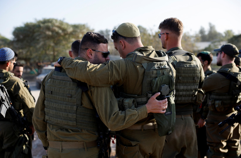  IDF soldiers embrace during briefing as they gather on the Israeli side of the Israel-Gaza border, amid the ongoing conflict between Israel and the Palestinian Islamist group Hamas, Israel December 11, 2023. (credit: AMIR COHEN/REUTERS)
