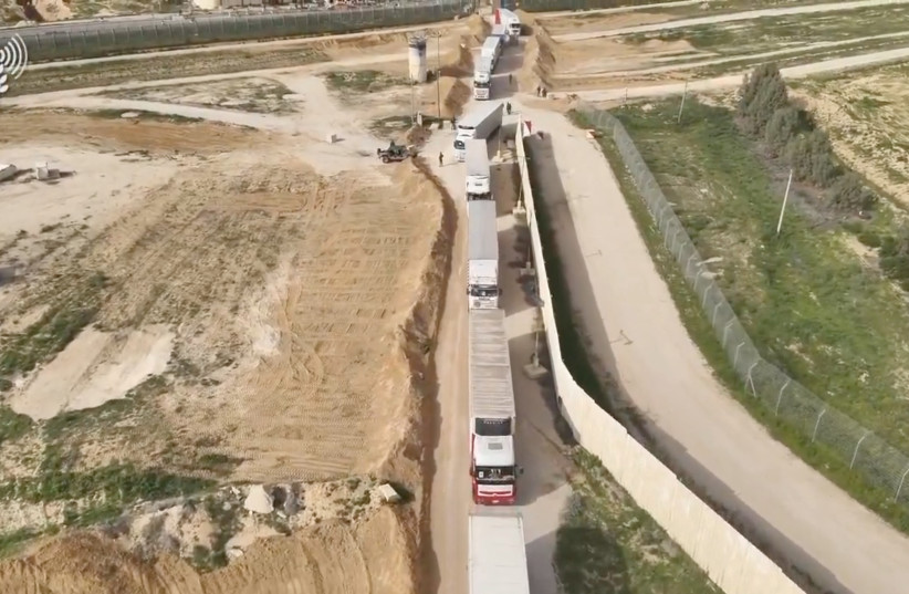   Humanitarian aid trucks wait in line to be inspected at the Kerem Shalom crossing, amid the ongoing conflict between Israel and the Palestinian terrorist group Hamas, on the border between Israel, Gaza and Egypt in this still image taken from video released December 12, 2023. (credit: COGAT via X/Handout via REUTERS)