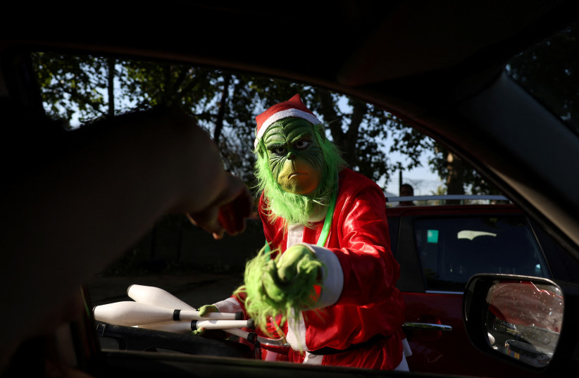 A person dressed as the Grinch stands next to a car, during Christmas season in Santiago, Chile, December 20, 2023. (credit: IVAN ALVARADO/REUTERS)