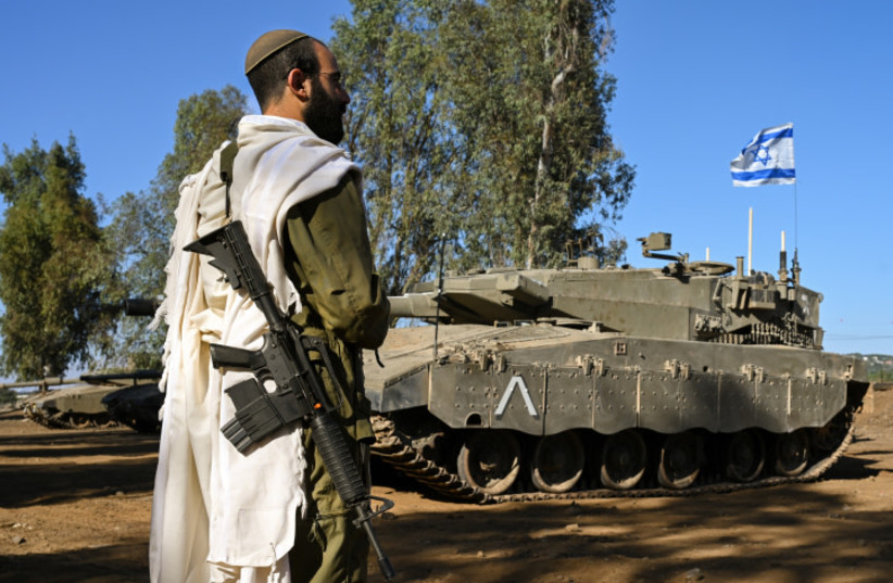  An Israeli soldier with a prayer shawl seen during a morning prayer near his tank near the border with Lebanon, northern Israel, October 25, 2023 (credit: MICHAL GILADI/FLASH90)