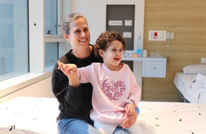  Abigail Idan, who was released after being taken hostage during the October 7 attack on Israel by the terrorist group Hamas, smiles on the lap of her aunt Liron at Schneider Children's Medical Center, November 27, 2023.  (credit: Schneider Children's Medical Center of Israel/Handout via REUTERS)