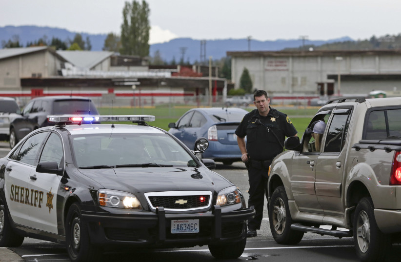  A County Sheriffs deputy stops traffic as police investigate a campus shooting in Marysville, Washington October 24, 2014. (credit: REUTERS/JASON REDMOND)
