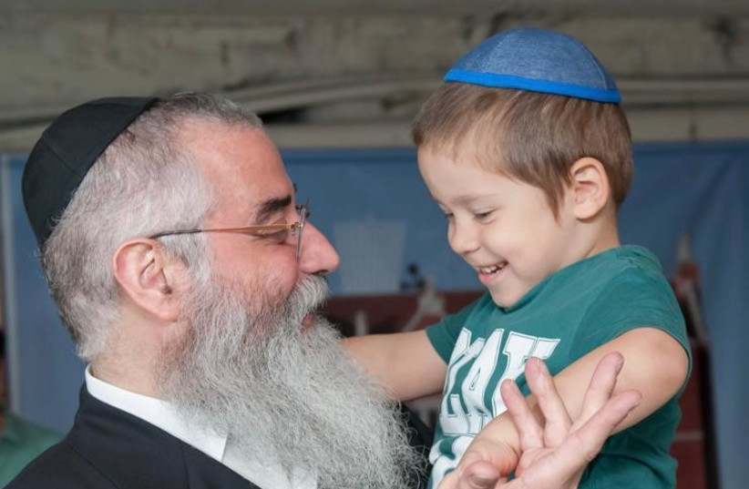 Rabbi Avraham Wolff holds little Mendy (Ccredit: Mishpacha Orphanage Odessa)