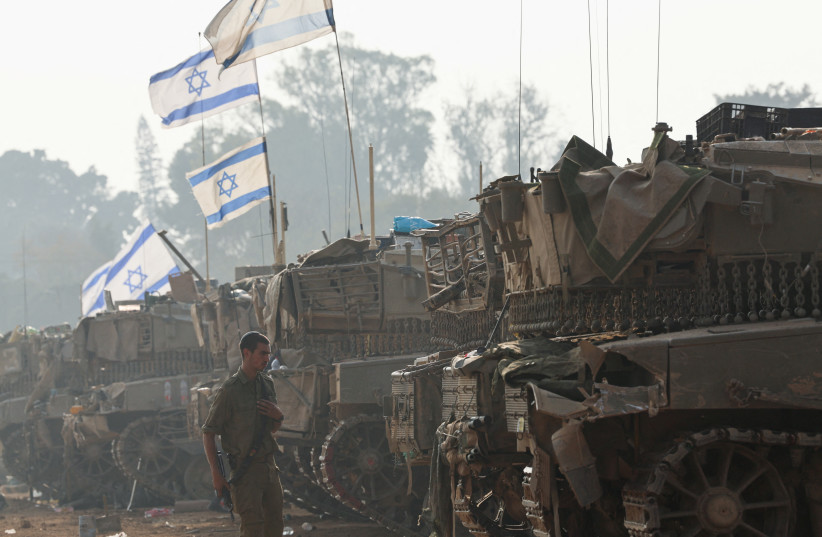  An Israeli soldier walks by tanks, amid the ongoing conflict between Israel and Hamas, near the Israel-Gaza border, in southern Israel, January 1, 2024 (credit: REUTERS/VIOLETA SANTOS MOURA)