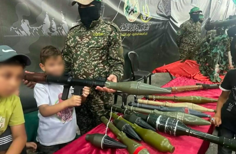 Gazan children pose with weapons and a member of the al-Qassam Brigades in this photo collected by the IDF (credit: IDF SPOKESPERSON'S UNIT)