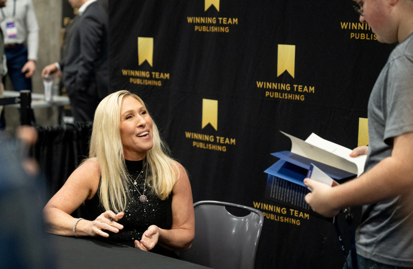  U.S. Representative Marjorie Taylor Greene (R-GA) talks with a fan during a book signing as conservative leaders and personalities attend Turning Point USA's AmericaFest 2023 in Phoenix, Arizona, U.S. December 17, 2023. (credit: REUTERS/Caitlin O’Hara)
