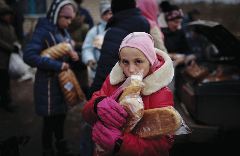  A CHILD holds loaves of bread given to her by a volunteer, at Kherson in Ukraine. (credit: NACHO DOCE/REUTERS)