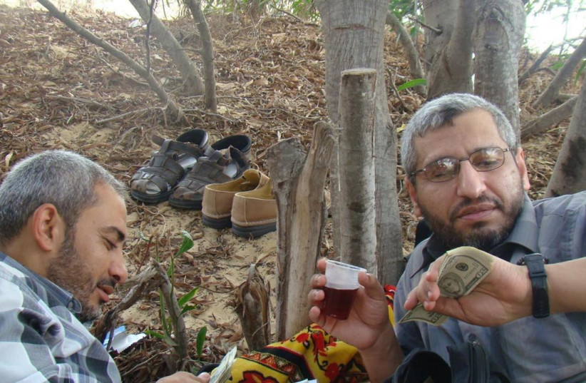 The newest photo of Muhammed Deif (right) holding US dollars and a plastic cup of juice. (credit: IDF SPOKESMAN’S UNIT)