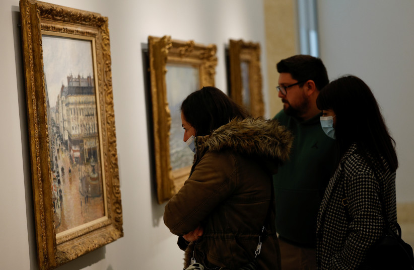  Visitors stand by Camille Pissarro's ''Rue Saint-Honore in the Afternoon. Effect of Rain, 1897'' at Thyssen-Bornemisza museum in Madrid, Spain, April 22, 2022. (credit: REUTERS/SUSANA VERA)