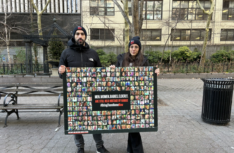  Shany Granot-Lubaton and her husband Omer hold up a sign filled with photos of the missing hostages in Gaza. (credit: HANNAH SARISOHN)