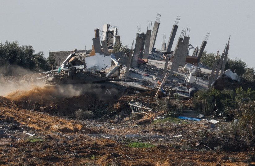A tank manoeuvres next to a destroyed building in central Gaza, amid the ongoing conflict between Israel and the Palestinian Islamist group Hamas, near the Israel-Gaza border, as seen from Israel, January 13, 2024.