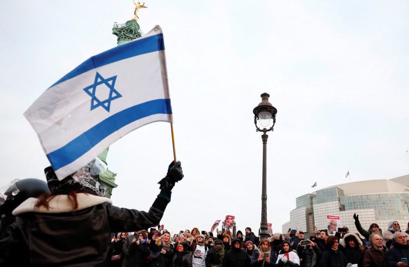  A woman waves an Israeli flag as people gather during the event ''100 days 100 voices'' to mark 100 days since the October 7 Hamas attack, calling for the release of Israeli hostages in Gaza, in front of the Opera Bastille in Paris, France, January 14, 2024 (credit: REUTERS/GONZALO FUENTES)